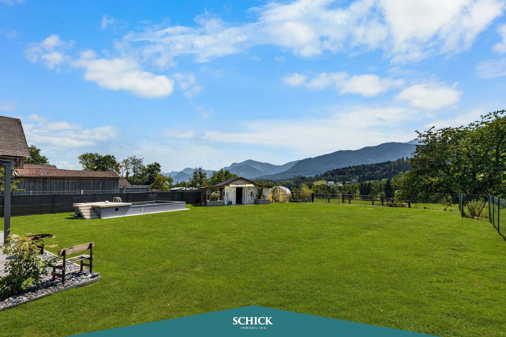 Weitläufige Rasenfläche des Gartens mit Blick auf das Haus und die Berglandschaft.