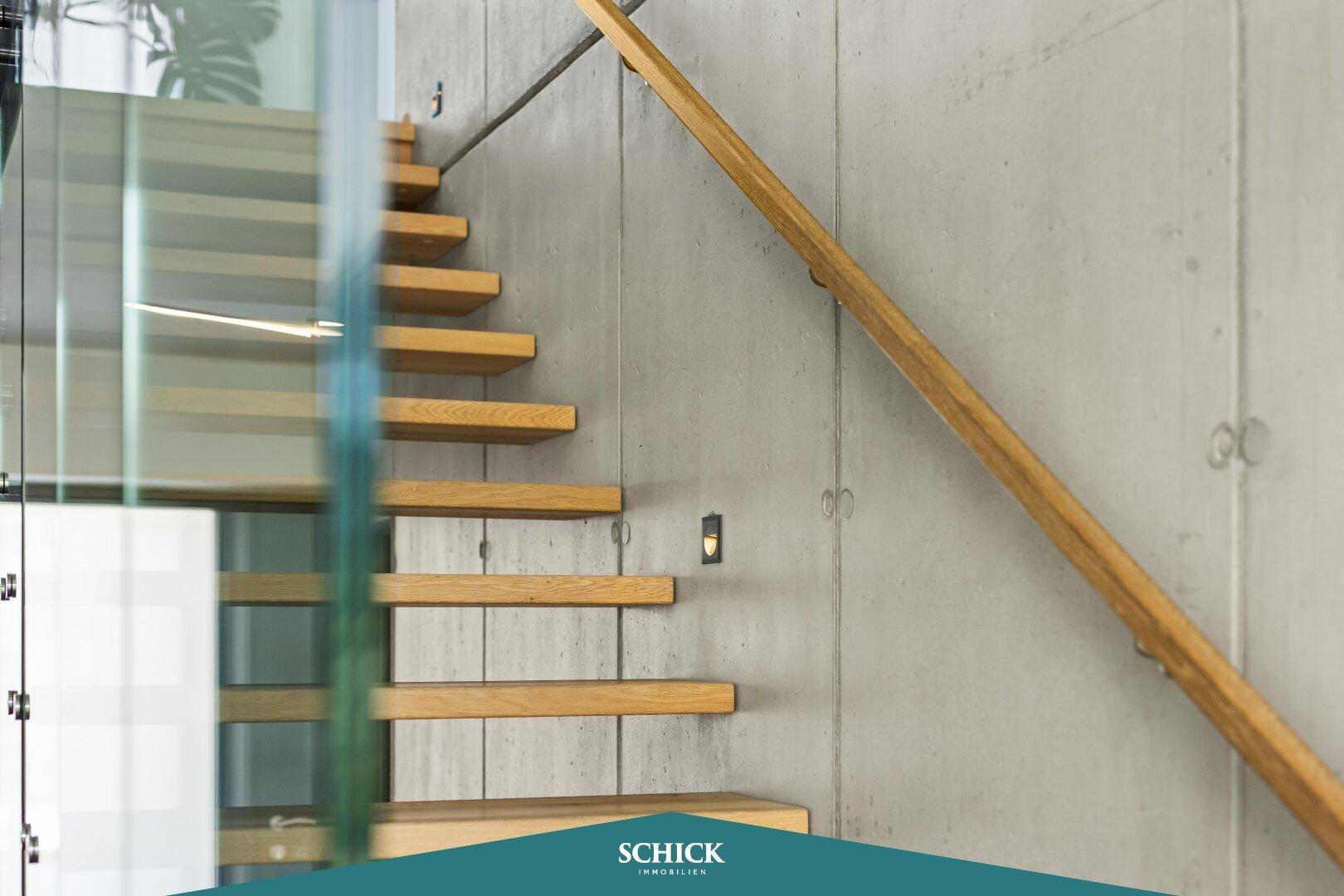 Detailansicht der modernen Treppe mit Holzstufen und Glasgeländer im Flurbereich.