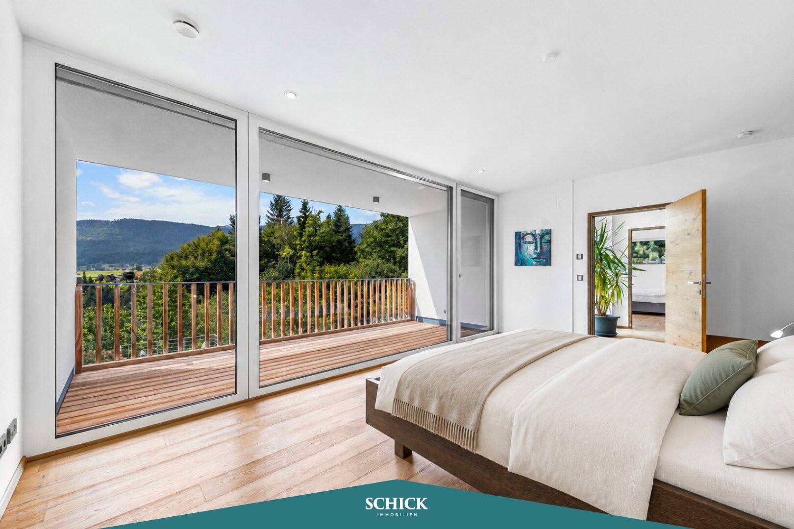 Schlafzimmer mit Balkonzugang und weitem Blick auf die umliegende Natur und Berge.