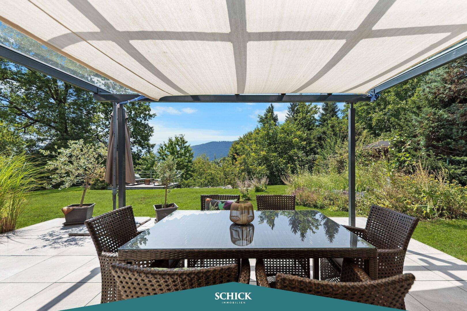 Überdachte Terrasse mit Esstisch und Stühlen, umgeben von viel Grün und Natur.