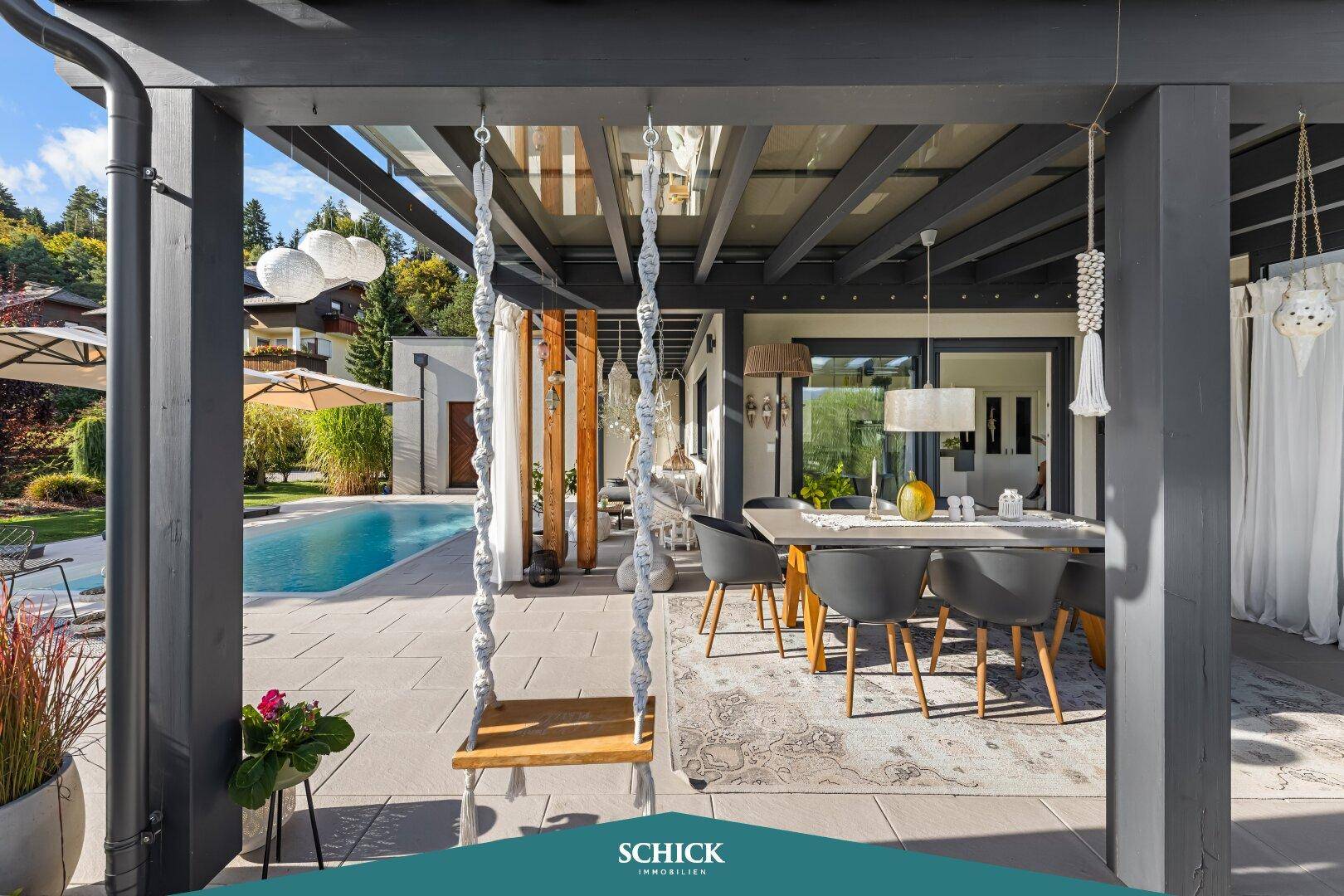 Überdachter Essbereich im Freien mit Schaukel und Blick auf den Pool und den Garten.