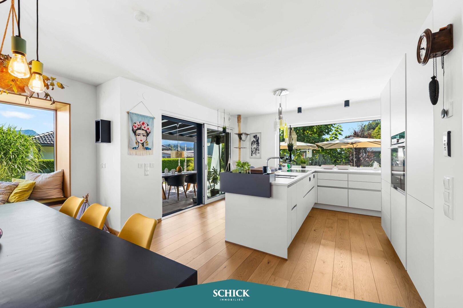 Moderne offene Küche mit Kochinsel und Essbereich, verbunden mit dem Wohnzimmer und Zugang zur Terrasse.