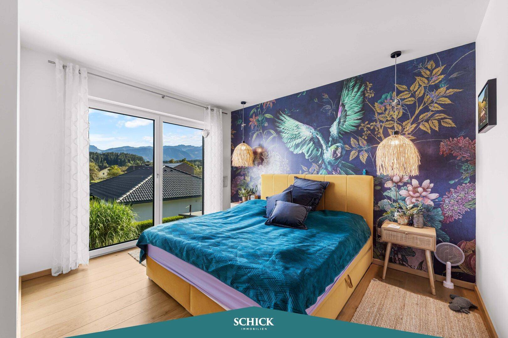 Schlafzimmer mit farbenfroher Tapete, Doppelbett und Zugang zu einem Balkon mit Bergblick.