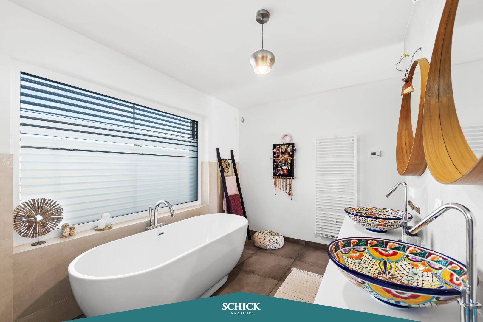 Modernes Badezimmer mit freistehender Badewanne, Doppelwaschbecken und großem Fenster.