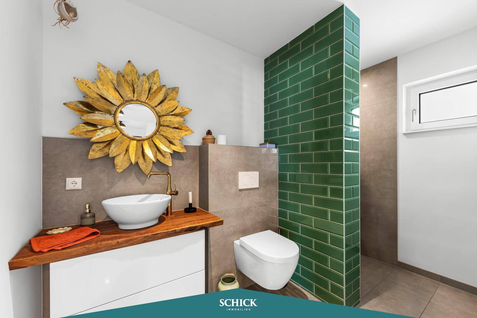 Modernes Badezimmer mit grünen Fliesen, Waschbecken auf Holzplatte und wandhängendem WC.