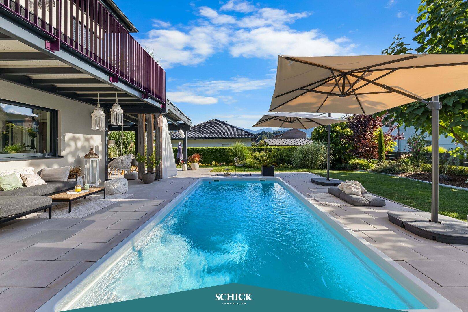 Moderner Außenbereich mit großem Pool, gepflasterter Terrasse und bequemen Lounge-Möbeln unter Sonnenschirmen.