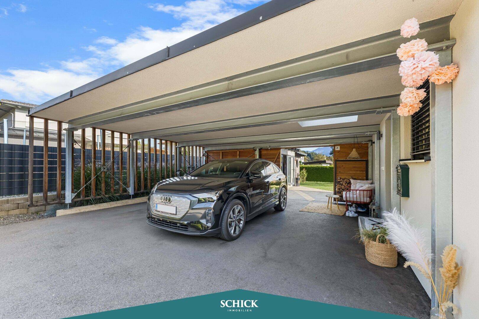 Geräumiger Carport mit Platz für ein Auto und Motorräder, seitlich mit Holzverkleidung.