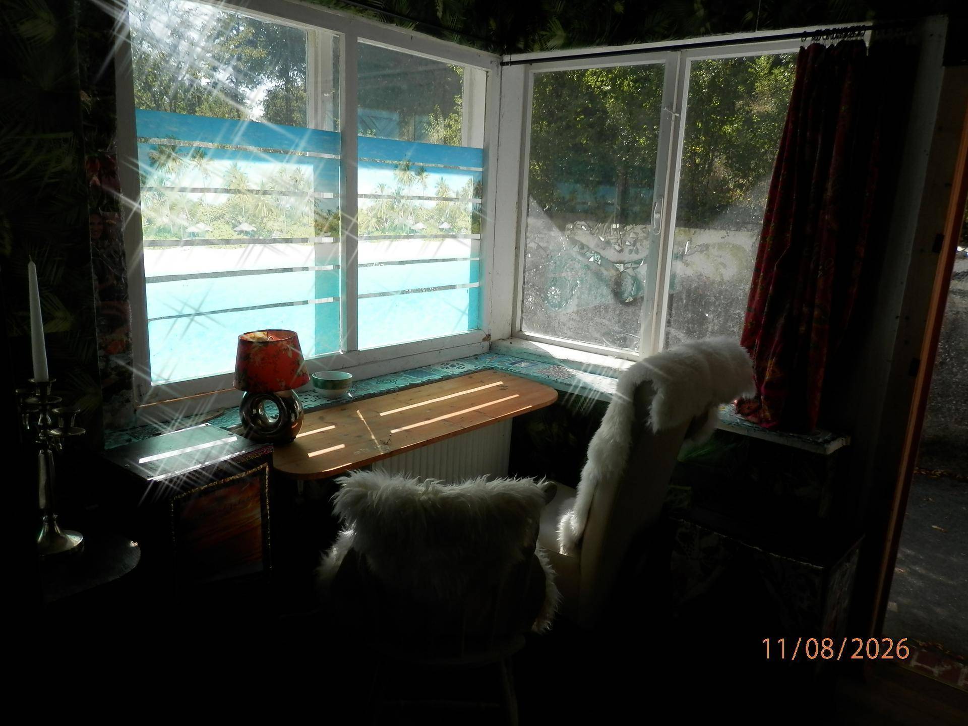 Helle Ecke mit Fenster, kleiner Ablage und dekorativer Lampe.