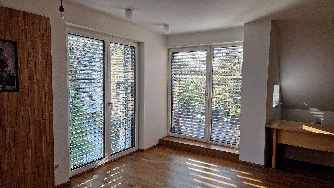 Heller Raum mit Holzboden, großen Fenstern und viel natürlichem Licht.