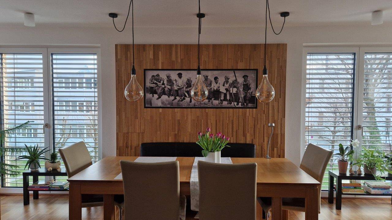 Heller Essbereich mit Holztisch, modernen Pendelleuchten und Holzwandverkleidung.