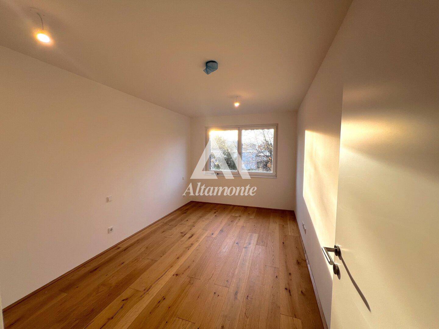Heller Raum mit Holzboden und Fenster, das viel natürliches Sonnenlicht hereinlässt.