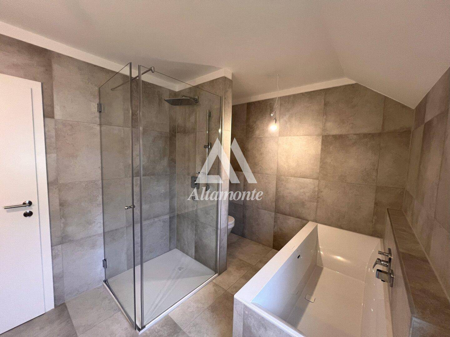 Modernes Badezimmer mit großer Duschkabine, Badewanne und grauen Fliesen.