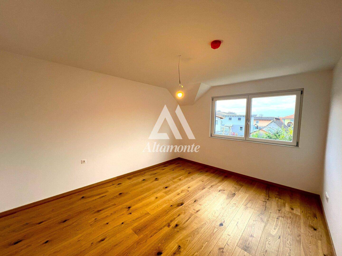 Freundliches Schlafzimmer mit Holzboden und Fenster, das eine angenehme Atmosphäre schafft.