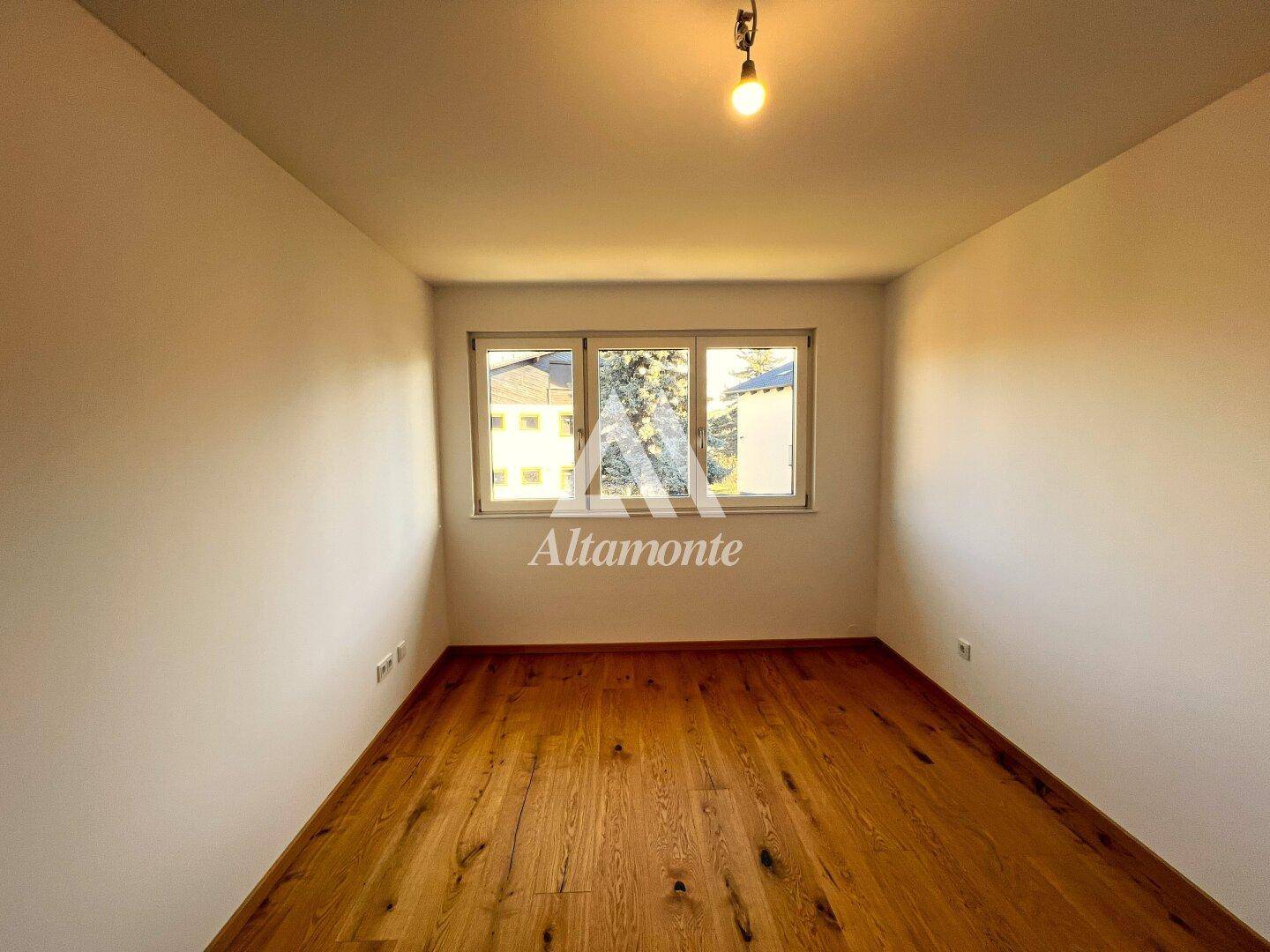 Helles, leeres Zimmer mit Holzboden und drei Fenstern, ideal als Schlaf- oder Kinderzimmer.