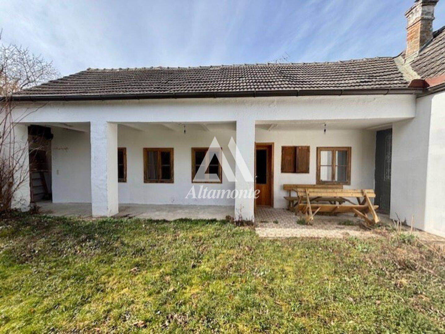 Überdachte Terrasse mit Holztisch und Bänken, ideal für Mahlzeiten im Freien.