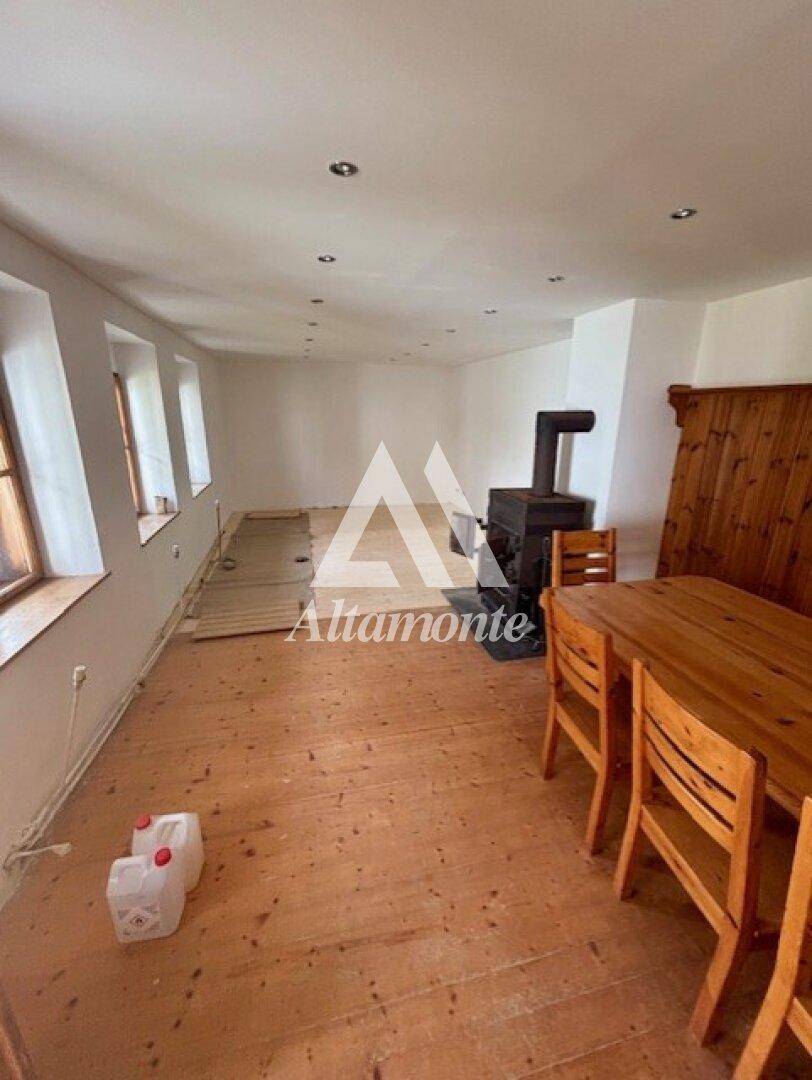 Geräumiger Wohn-Essbereich mit Holzboden, Kaminofen und rustikalem Esstisch.