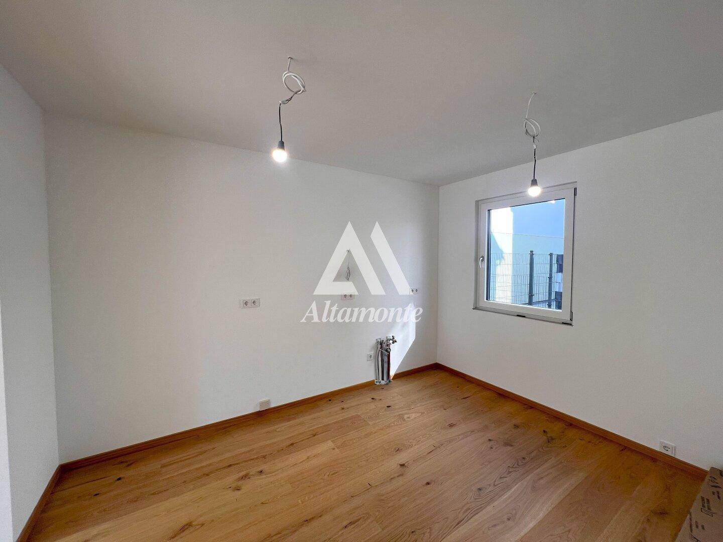 Helles Zimmer mit Eichenparkettboden und einem Fenster, ideal als Schlaf- oder Arbeitszimmer.