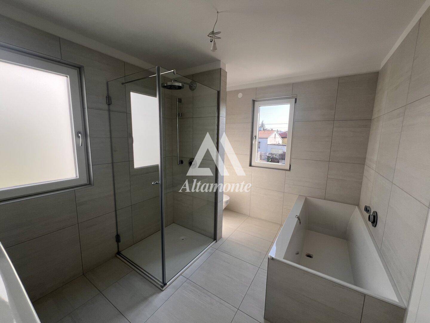 Modernes Badezimmer mit großen Fliesen, begehbarer Dusche und integrierter Badewanne.