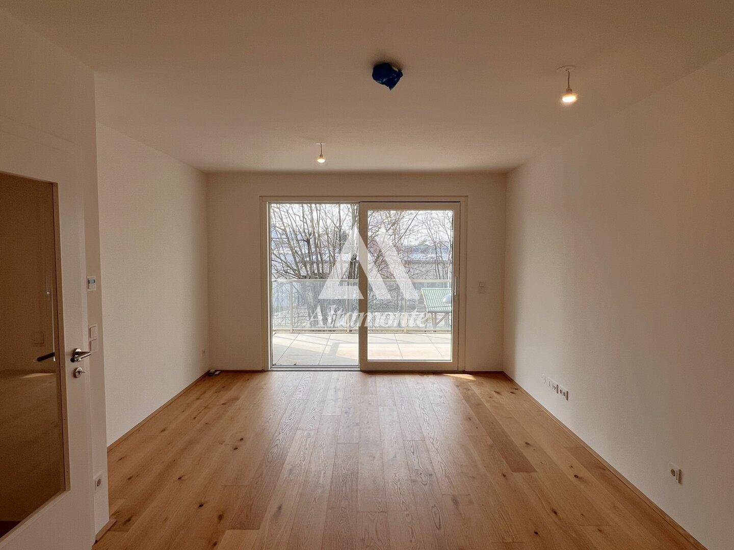 Helles Wohnzimmer mit neuem Parkettboden und großem Schiebefenster zum Balkon.
