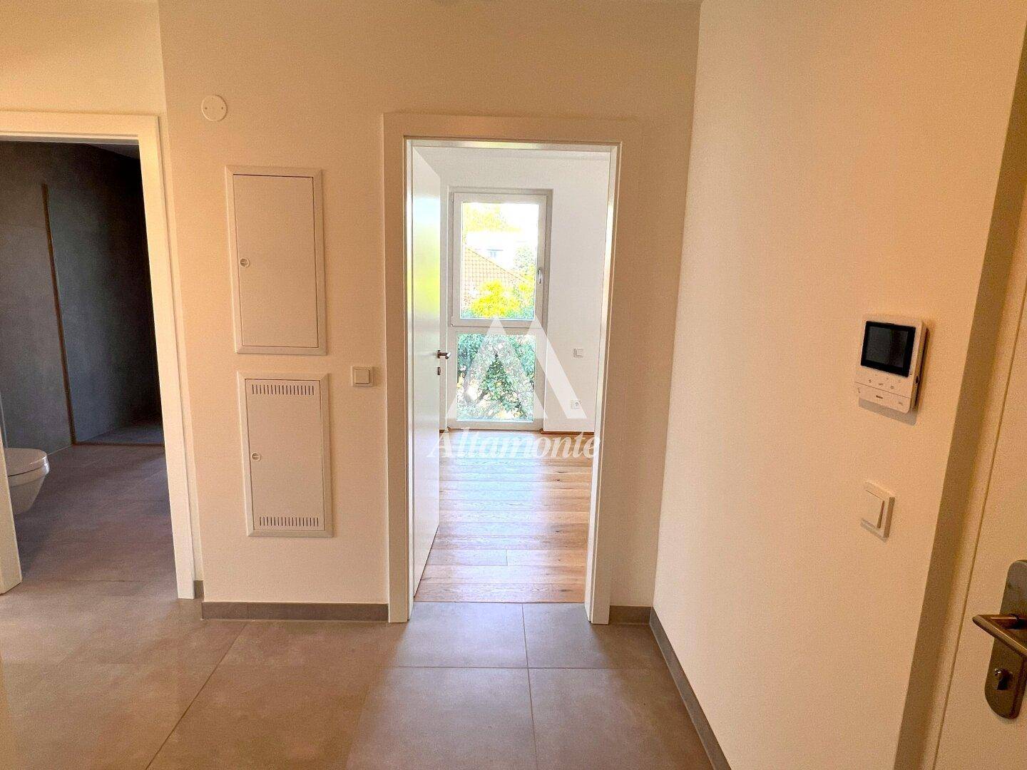 Heller Flur mit Fliesenboden und Zugang zu verschiedenen Räumen der Wohnung.