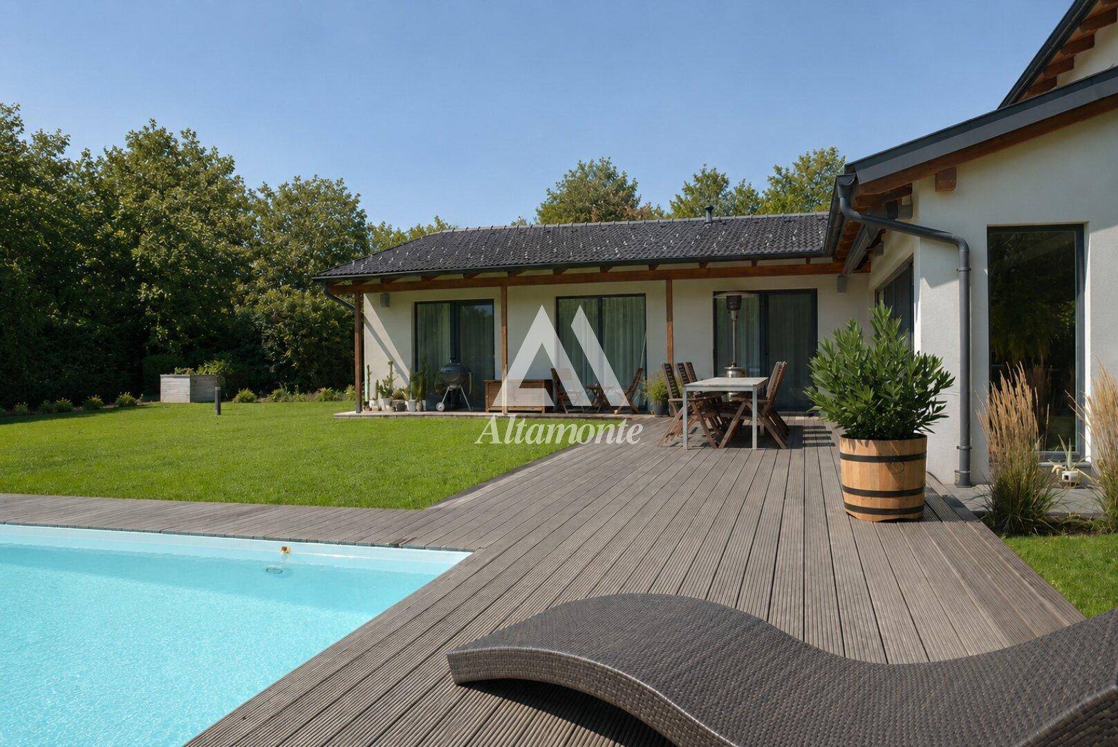 Weitläufiger Gartenbereich mit Pool, Holzterrasse und Essbereich im Freien neben dem Haus.
