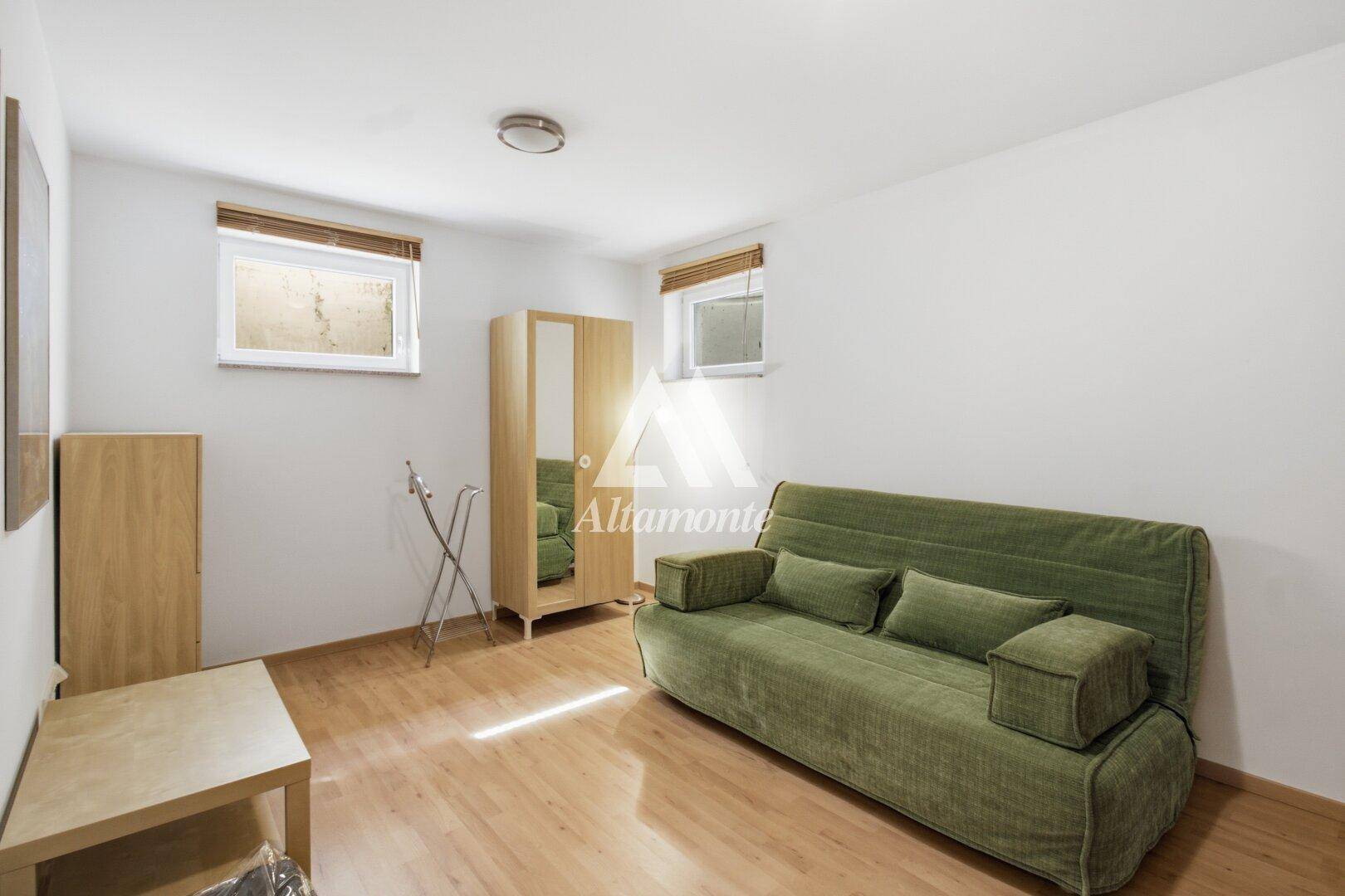 Vielseitig nutzbarer Raum im Untergeschoss mit Sofa und kleinem Fenster.