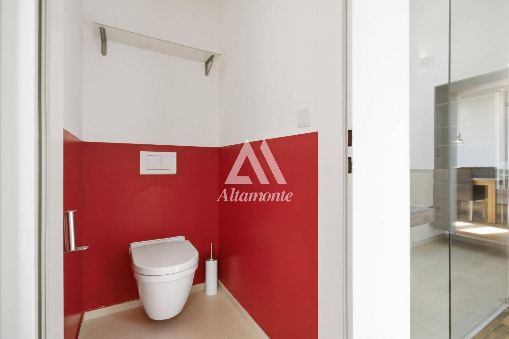 Kleines Gäste-WC mit wandhängender Toilette und auffälliger roter Wandgestaltung.