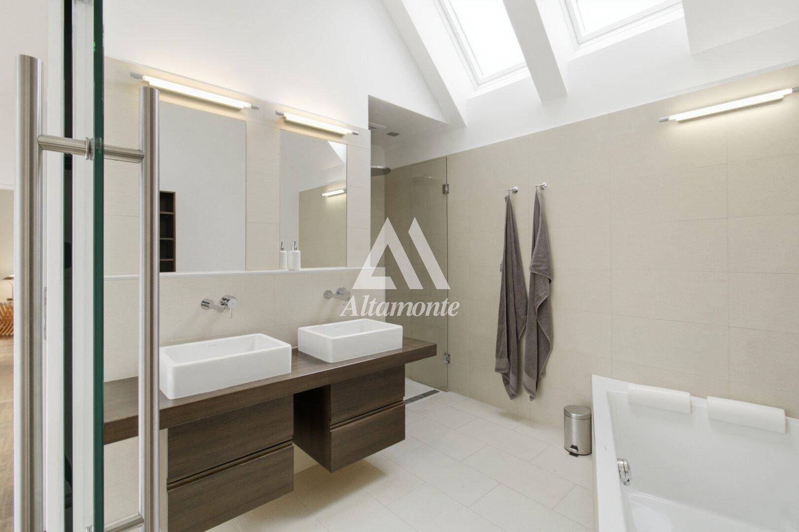 Modernes Badezimmer mit Doppelwaschbecken, großer Dusche und Badewanne unter Dachfenstern.