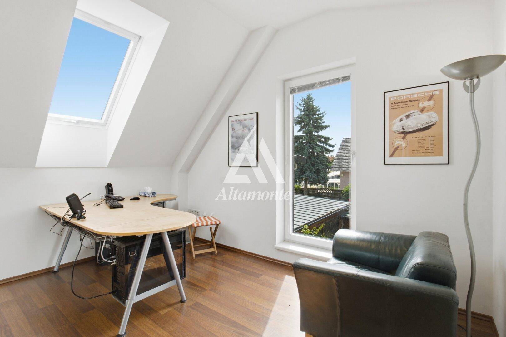 Arbeitszimmer mit Holzboden, Schreibtisch und Dachfenster für viel Tageslicht.