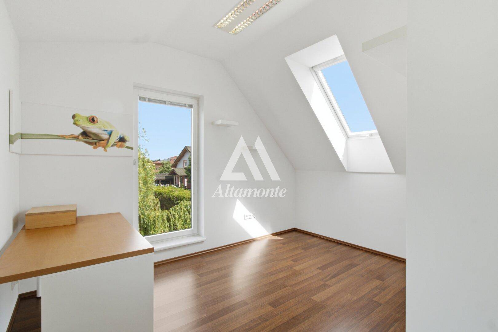 Leeres Zimmer mit Holzboden, Dachfenster und Blick ins Grüne, ideal als Kinderzimmer.