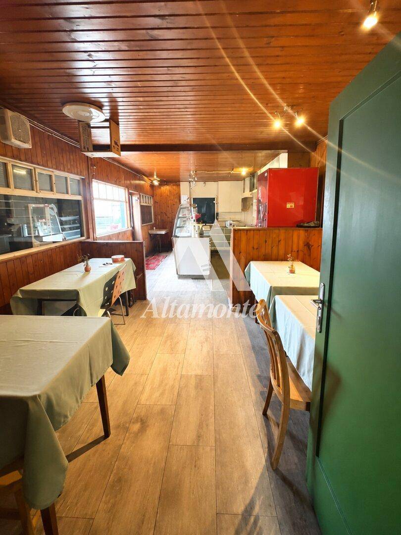 Gemütlicher Innenraum eines Restaurants mit Holzwänden, Holzboden und Tischen mit hellen Tischdecken.