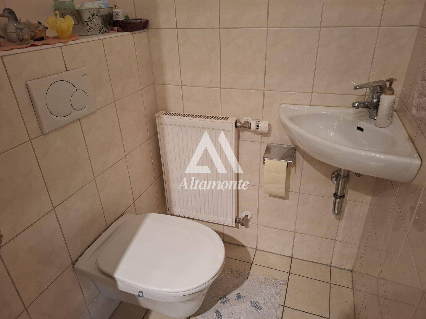 Kleines Gäste-WC mit wandhängender Toilette, Eckwaschbecken und gefliesten Wänden.
