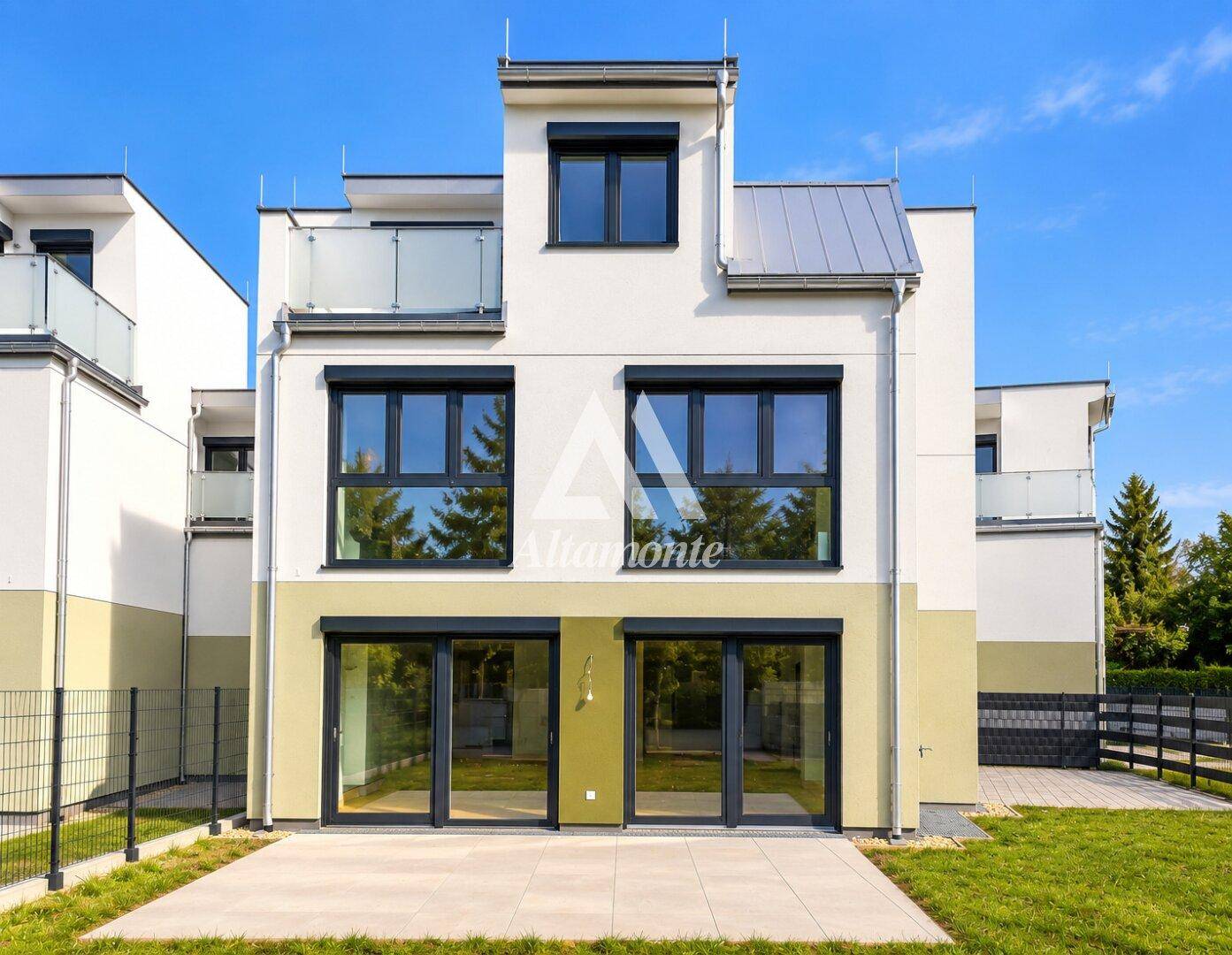 Rückansicht des modernen Reihenhauses mit weißer Fassade, großen Fenstern und Rasenfläche.