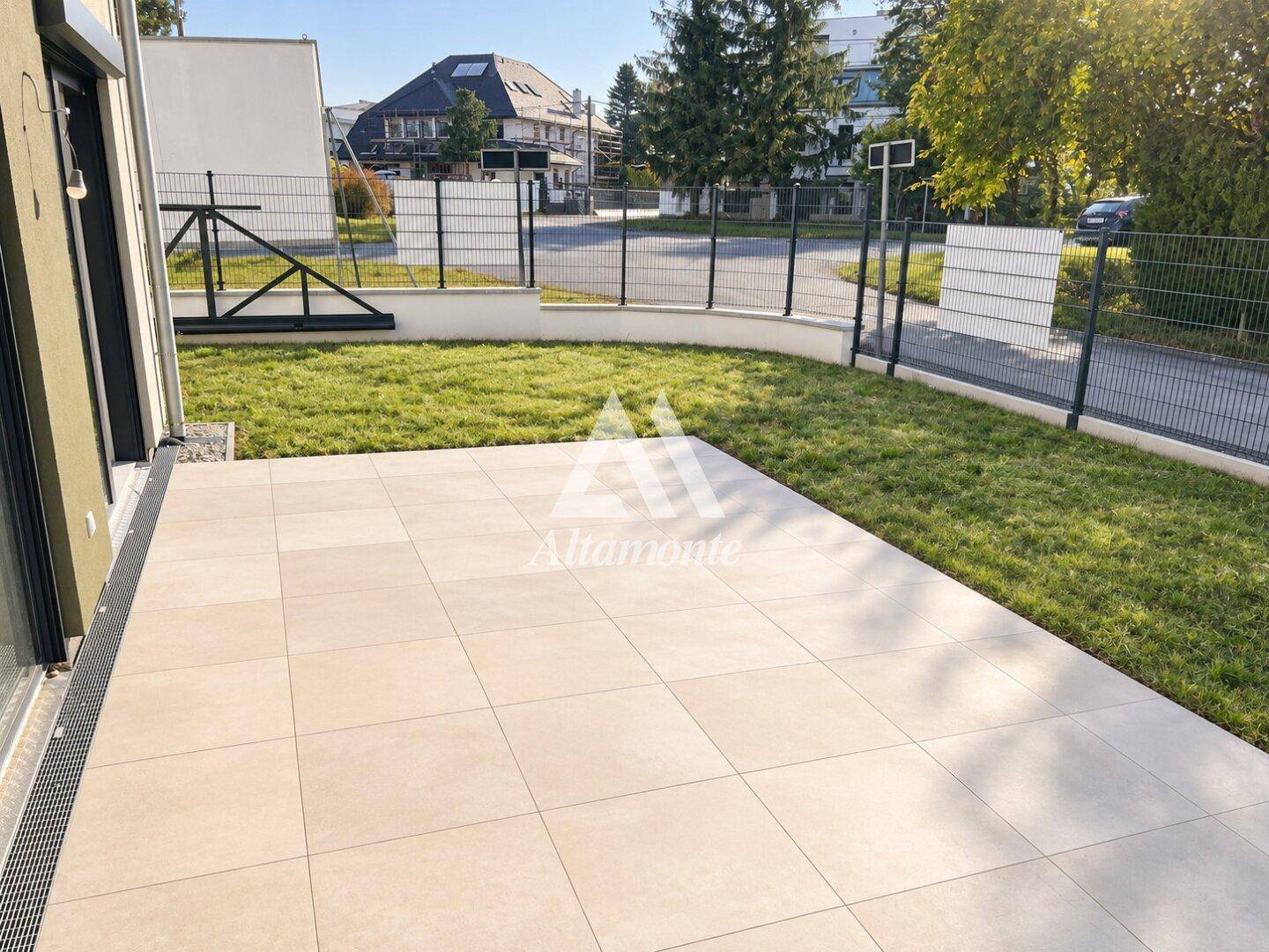Geräumige, geflieste Terrasse mit angrenzendem Rasenbereich und Blick auf die Umgebung.