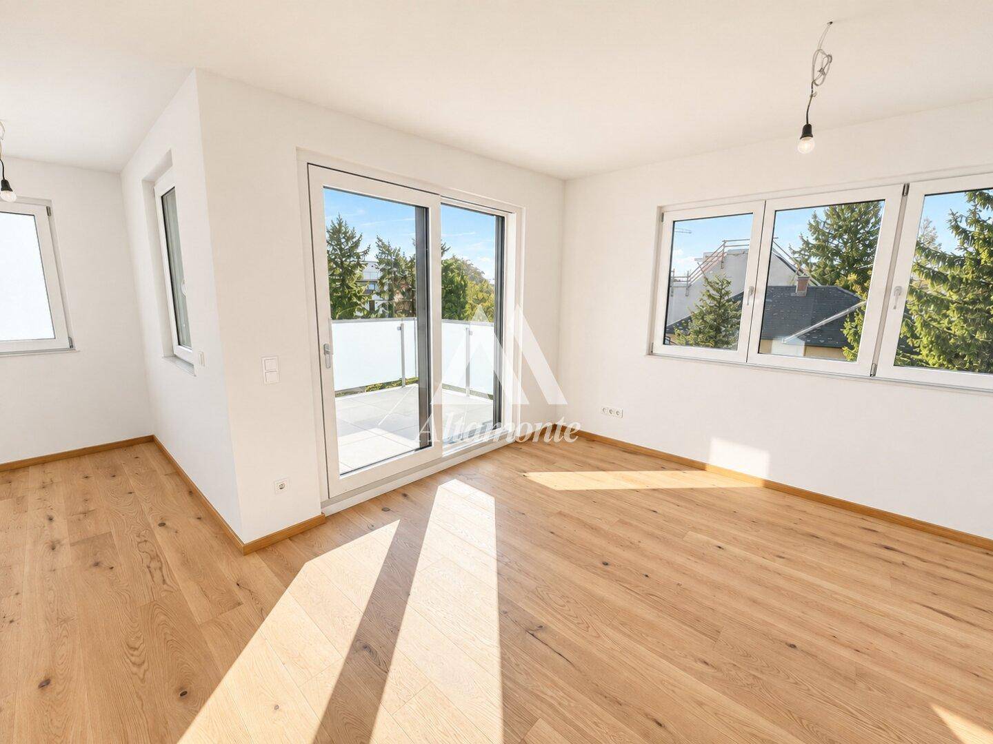 Schlafzimmer mit Holzboden, großen Fenstern und direktem Zugang zu einem Balkon.