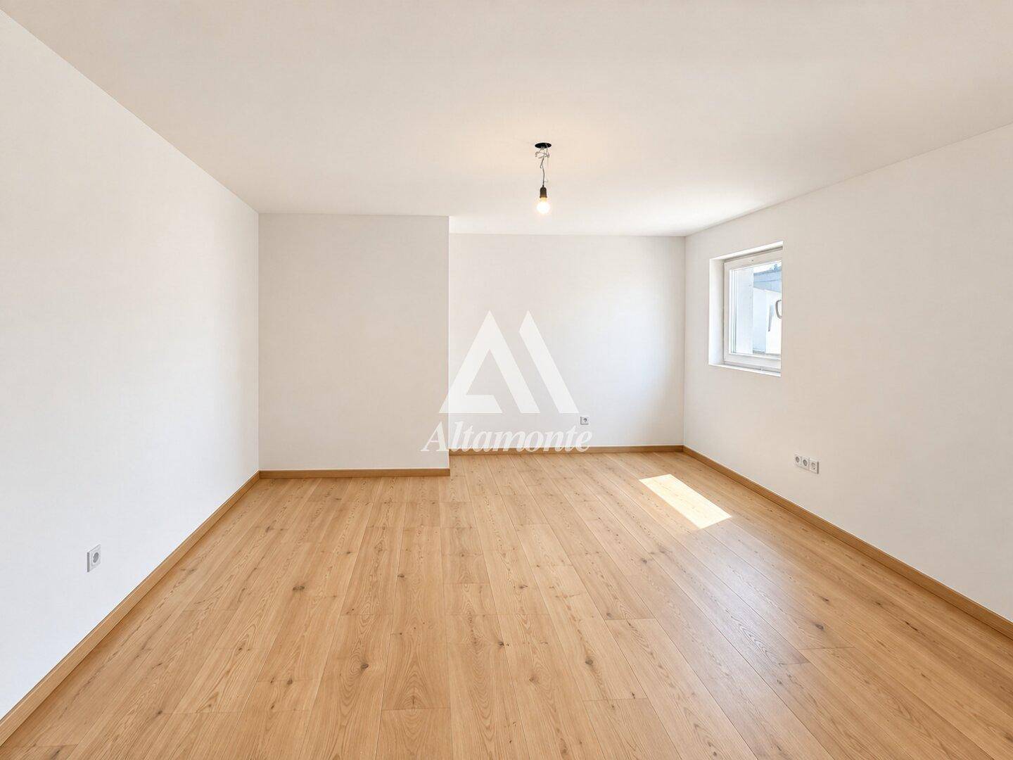 Helles Zimmer mit Holzboden und einem Fenster, das viel Tageslicht hereinlässt.