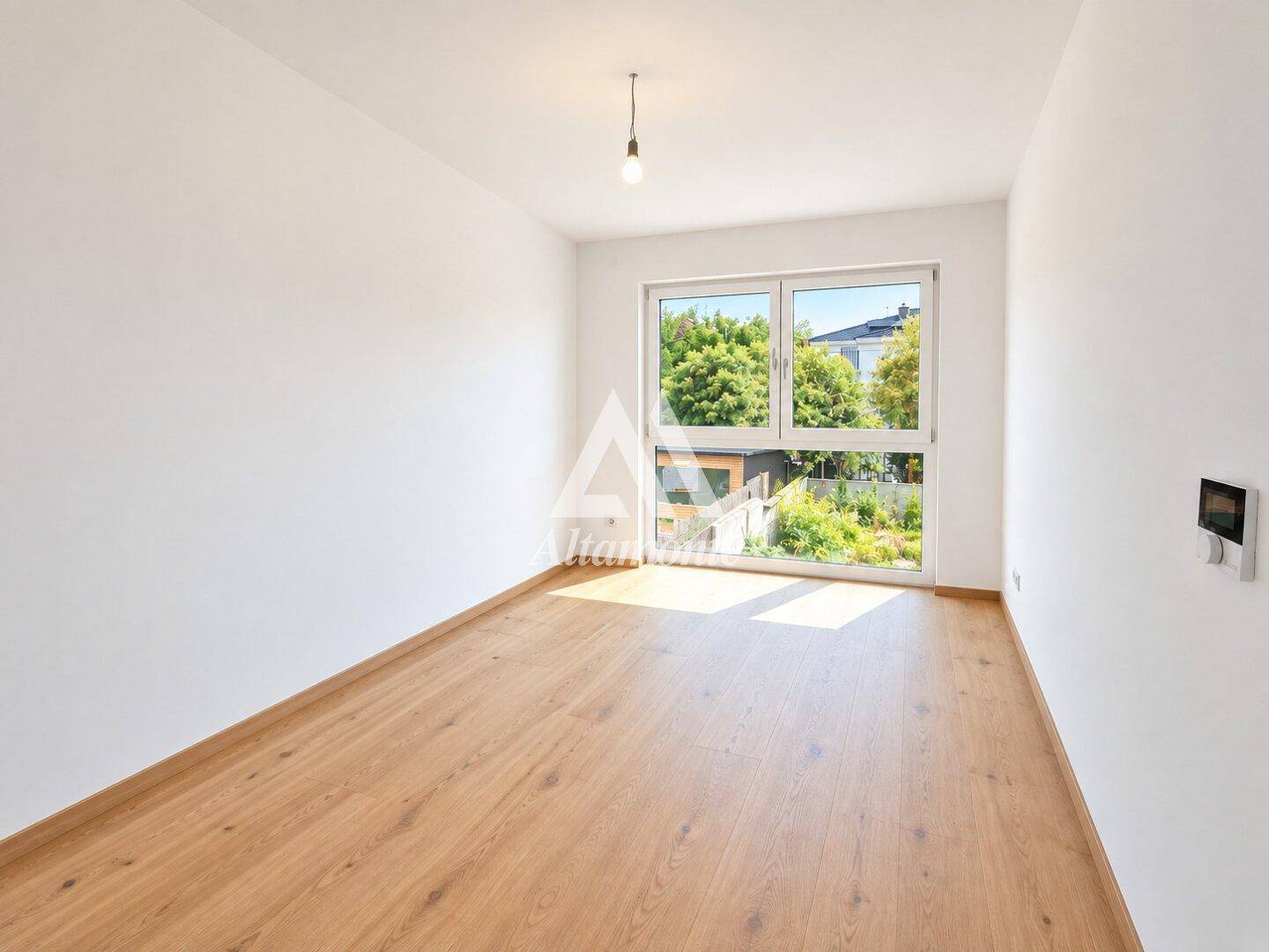 Schlafzimmer mit Holzboden und großen Fenstern, die einen schönen Blick ins Grüne bieten.