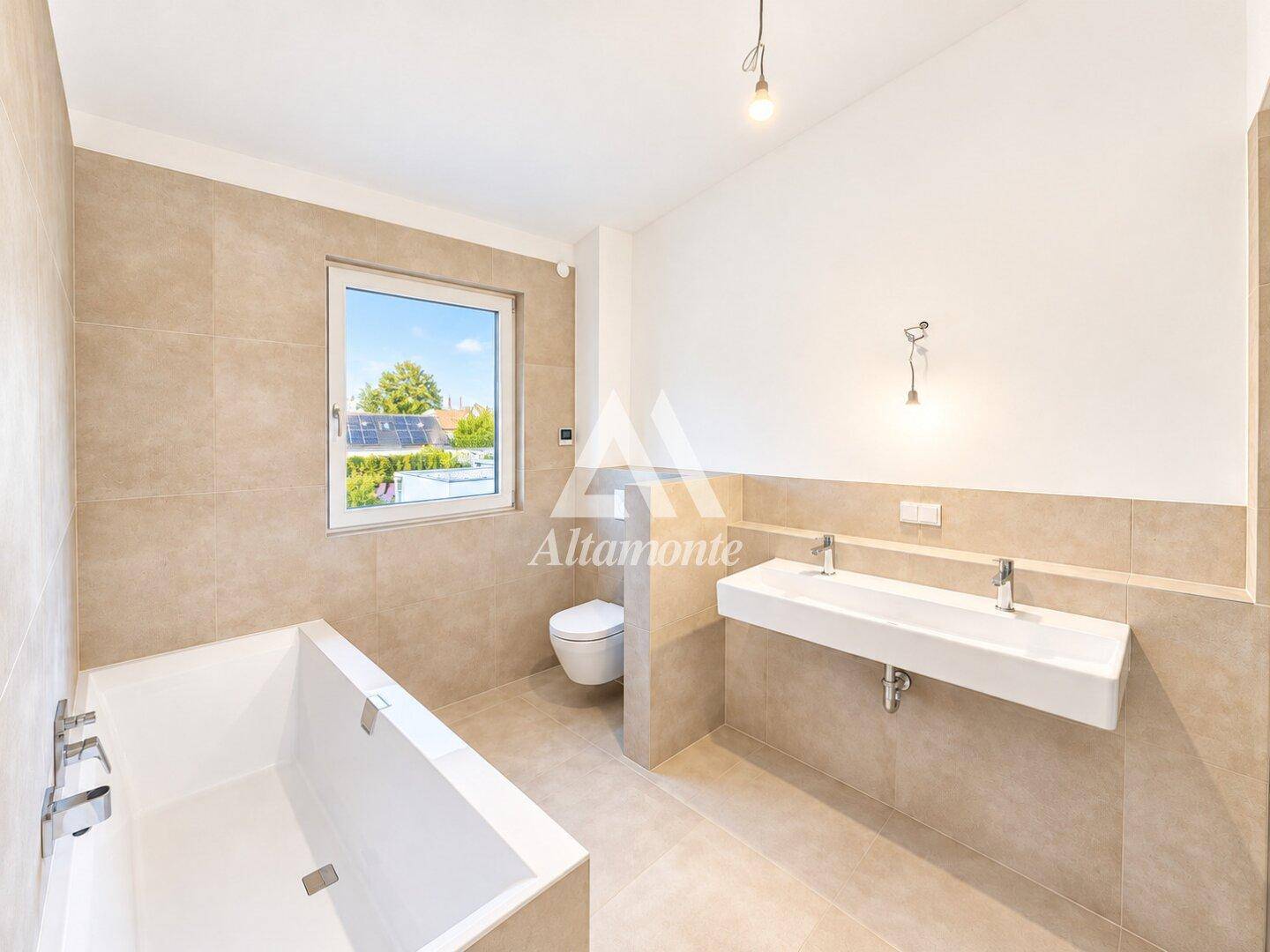 Modernes Badezimmer mit Badewanne, Doppelwaschbecken und großformatigen Fliesen.