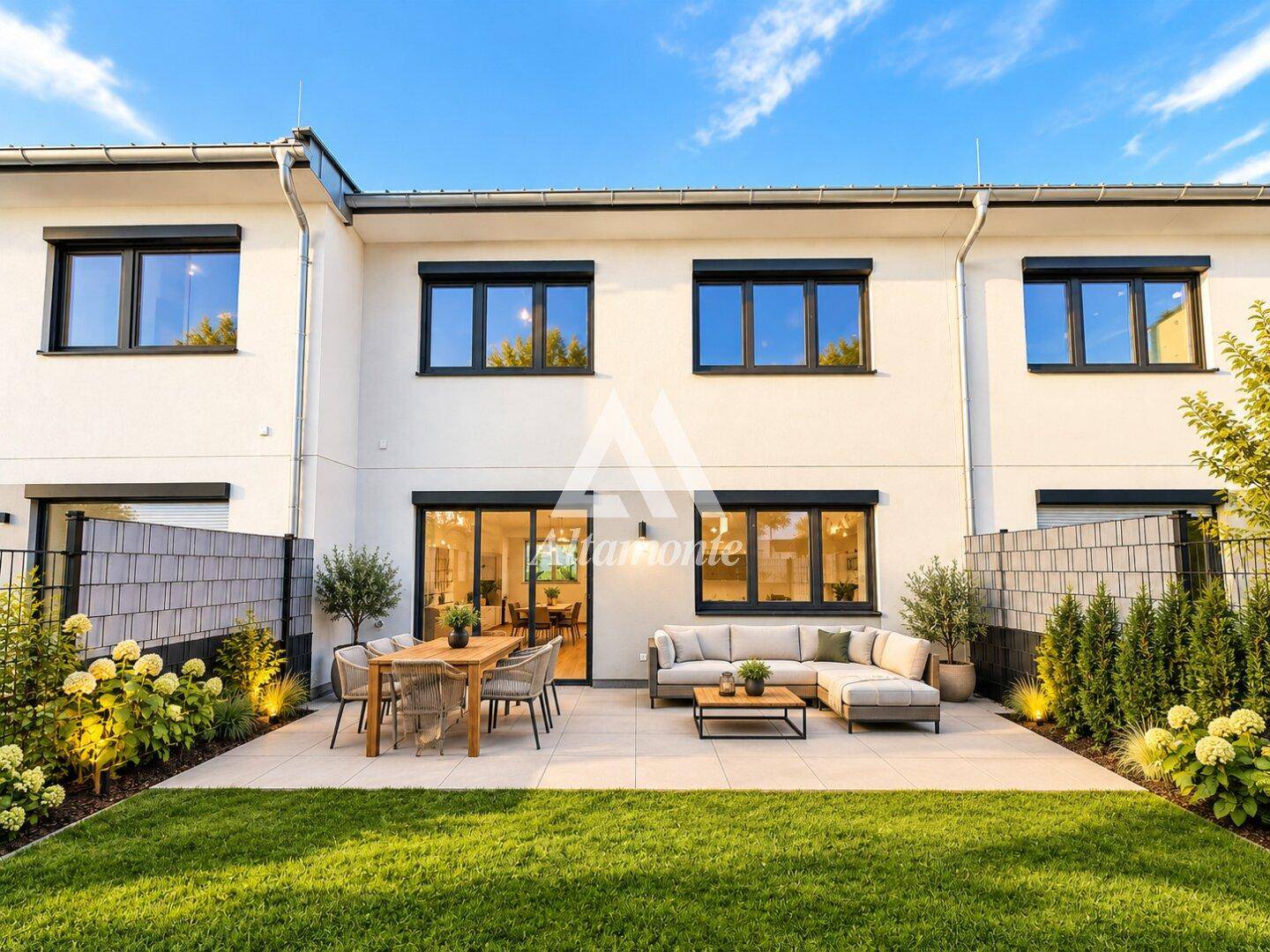 Attraktive Terrasse mit Gartenmöbeln und gepflegtem Rasen hinter dem Haus.