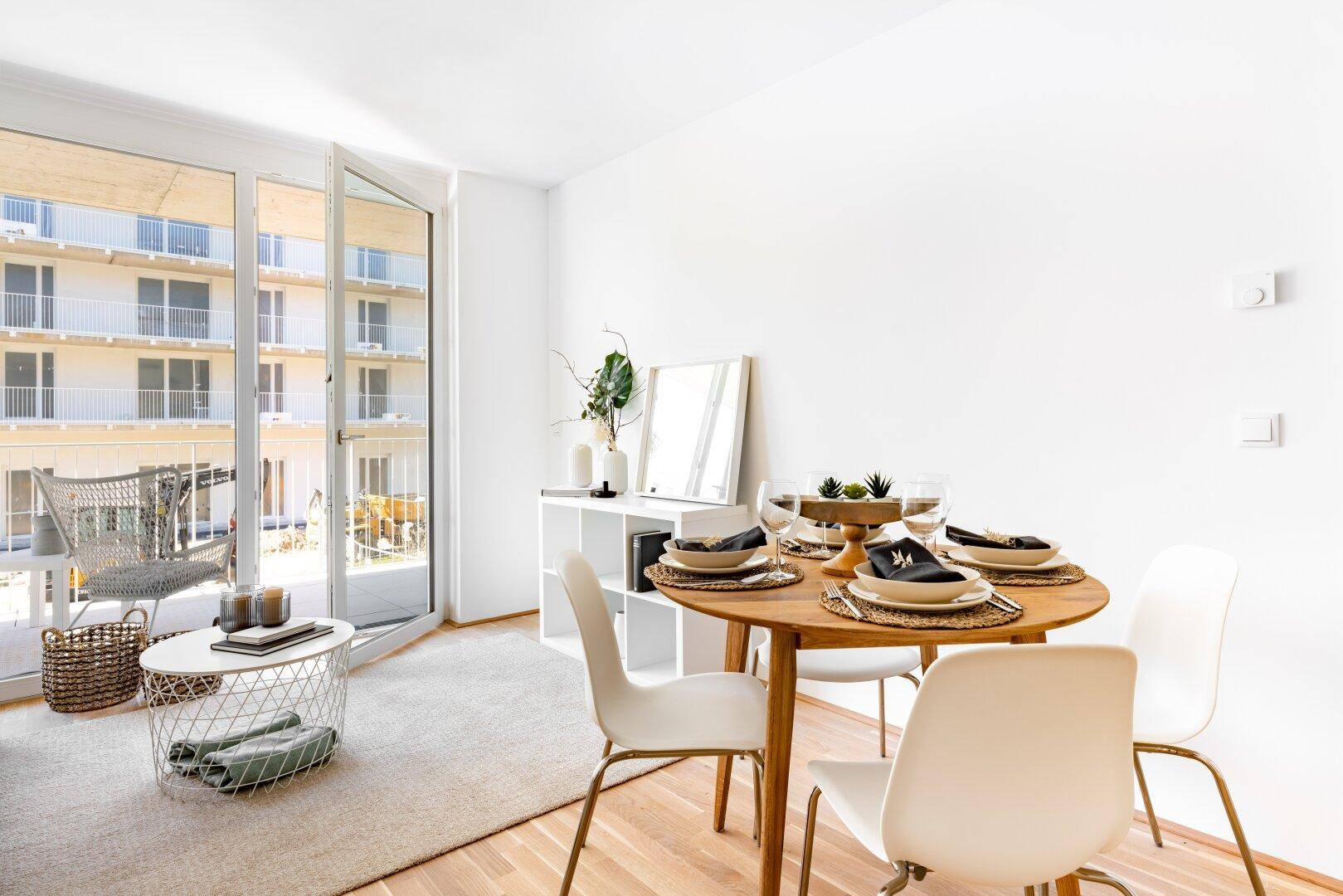 Heller Essbereich mit Holztisch, modernen Stühlen und Zugang zu einem Balkon.