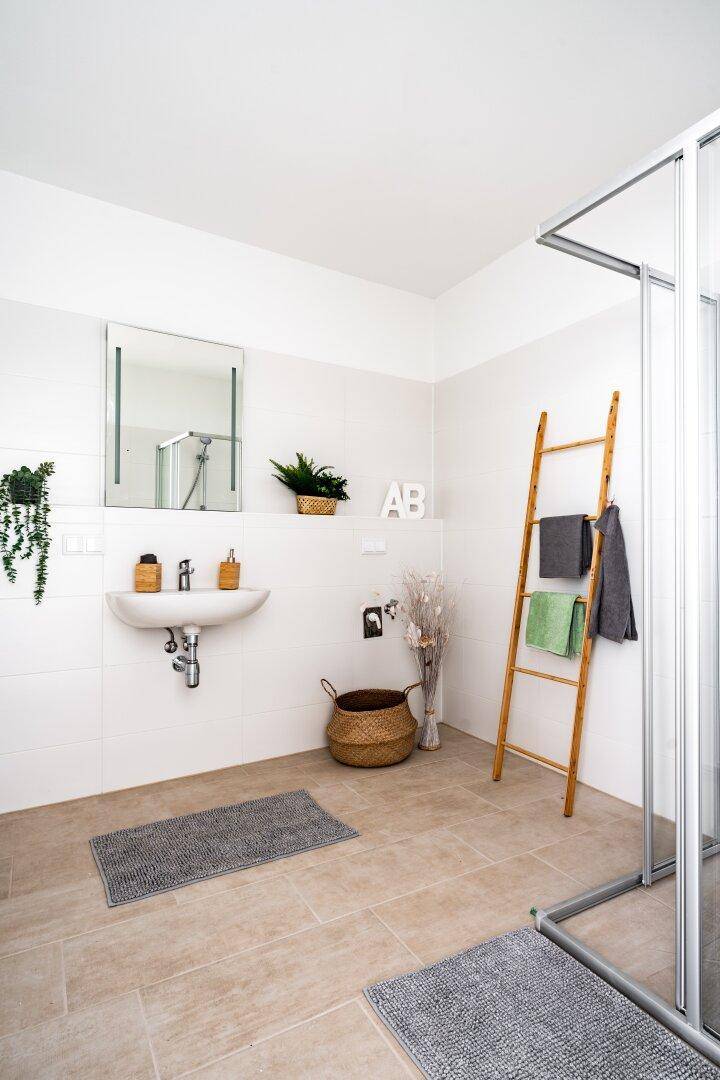 Modernes Badezimmer mit begehbarer Dusche, Einzelwaschbecken und hellen Fliesen.