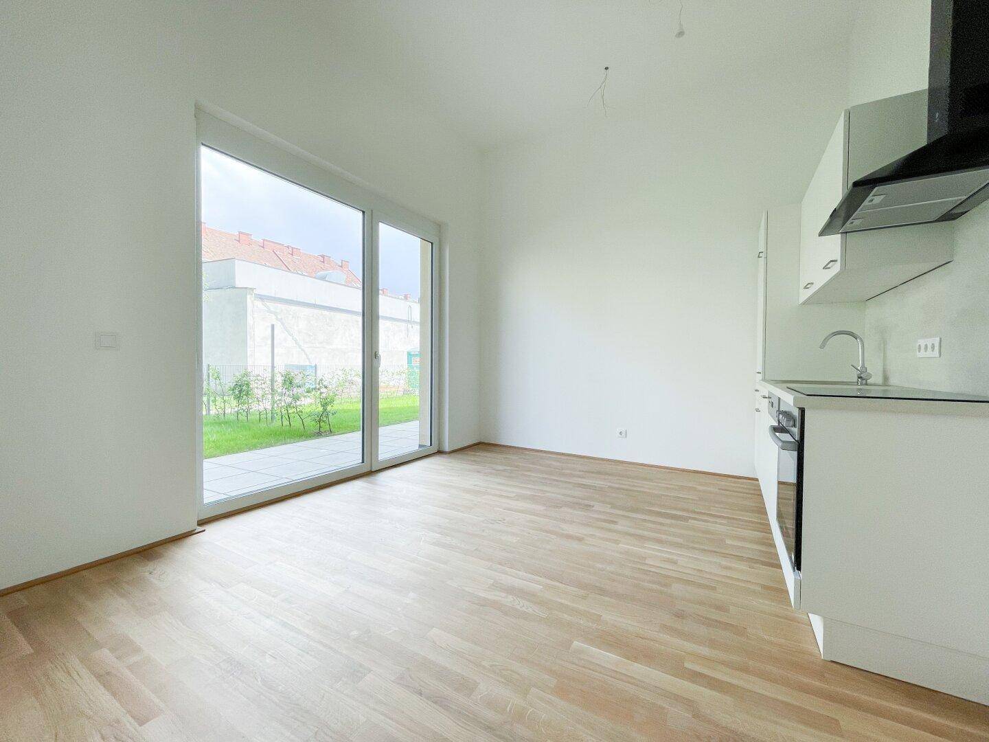 Heller Wohnbereich mit großen Schiebetüren zum Garten und hellem Holzparkettboden.