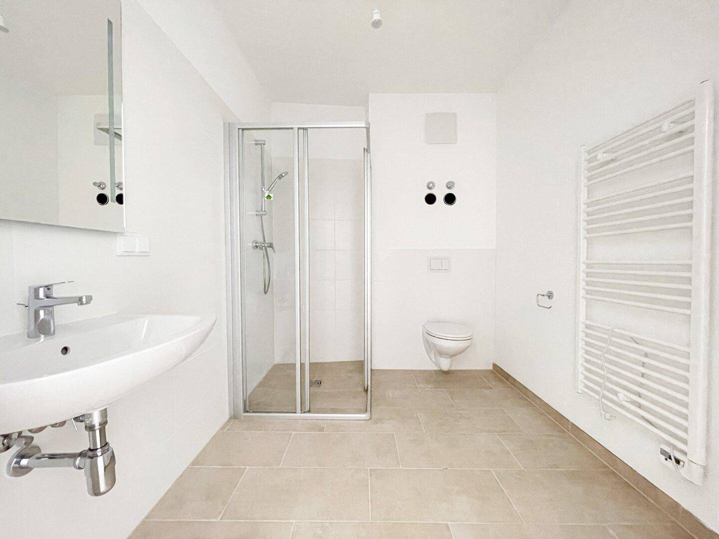 Modernes Badezimmer mit Fliesenboden, Duschkabine, wandhängendem WC und Handtuchheizkörper.
