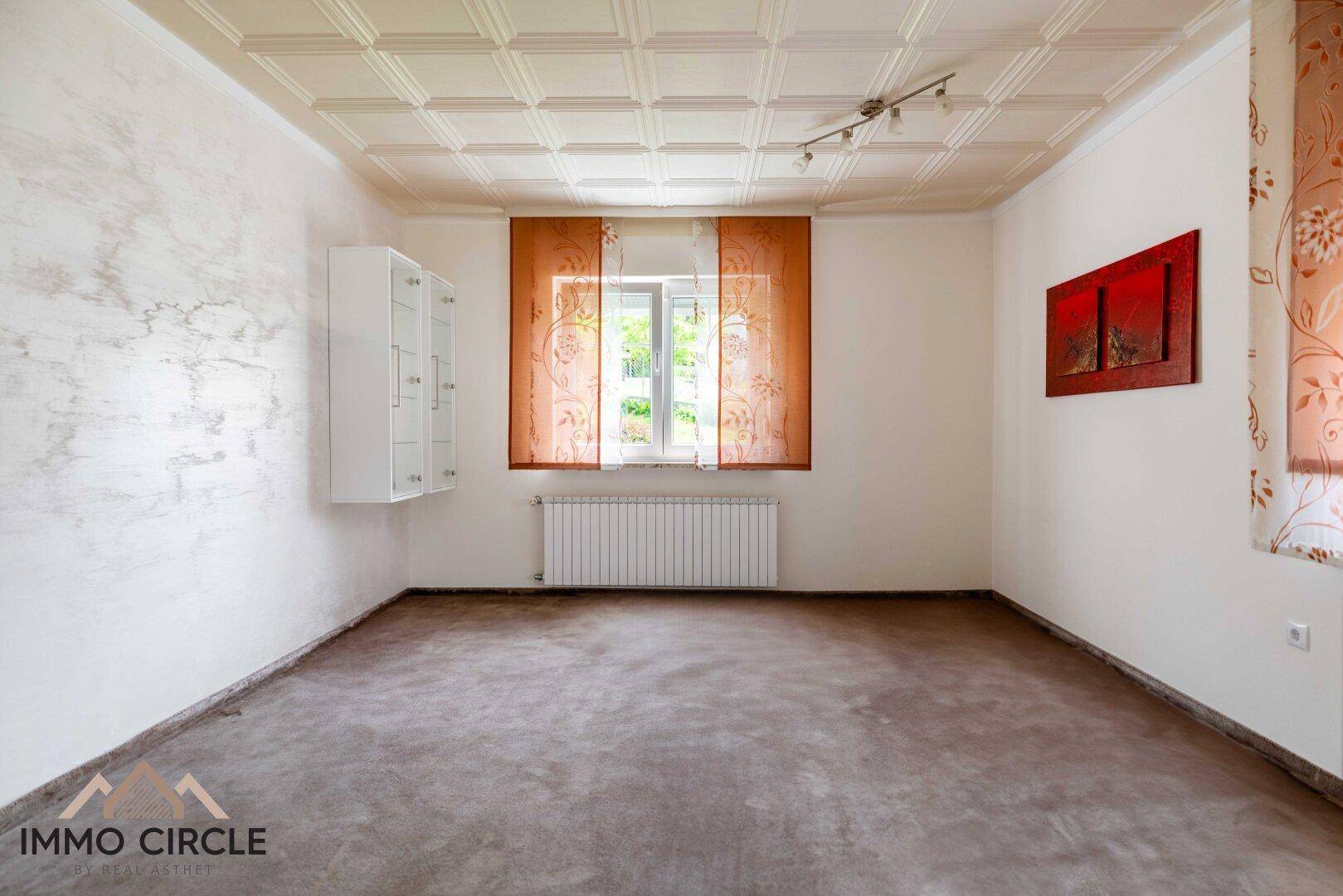 Geräumiges Zimmer mit strukturierter Decke, Fenster und Heizkörper.