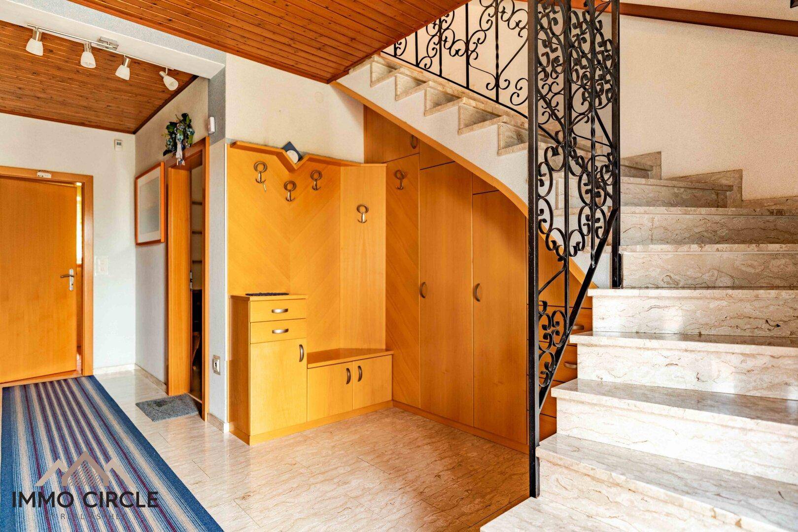 Geräumiger Flur mit Marmortreppe, Garderobe und Holzdecke.