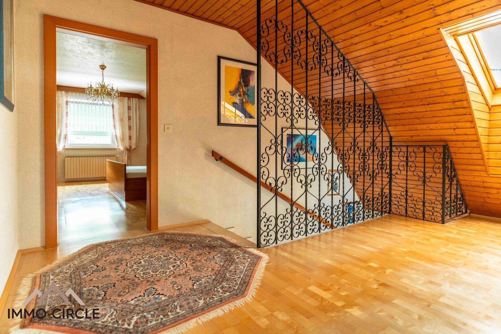 Heller Flur im Obergeschoss mit Holzparkett, Dachschräge und Zugang zu Zimmern.