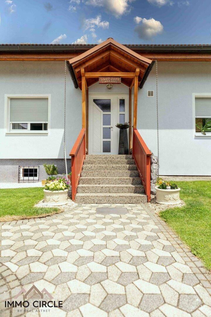 Hauseingang mit überdachtem Vordach, Treppe und gepflastertem Weg.