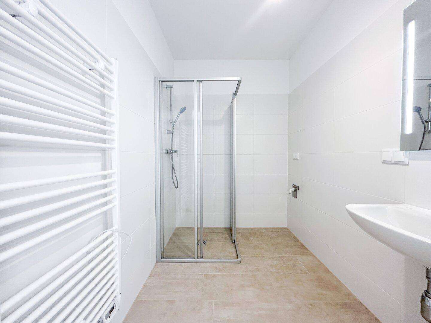 Helles Badezimmer mit Duschkabine, Einzelwaschbecken und praktischem Handtuchheizkörper.