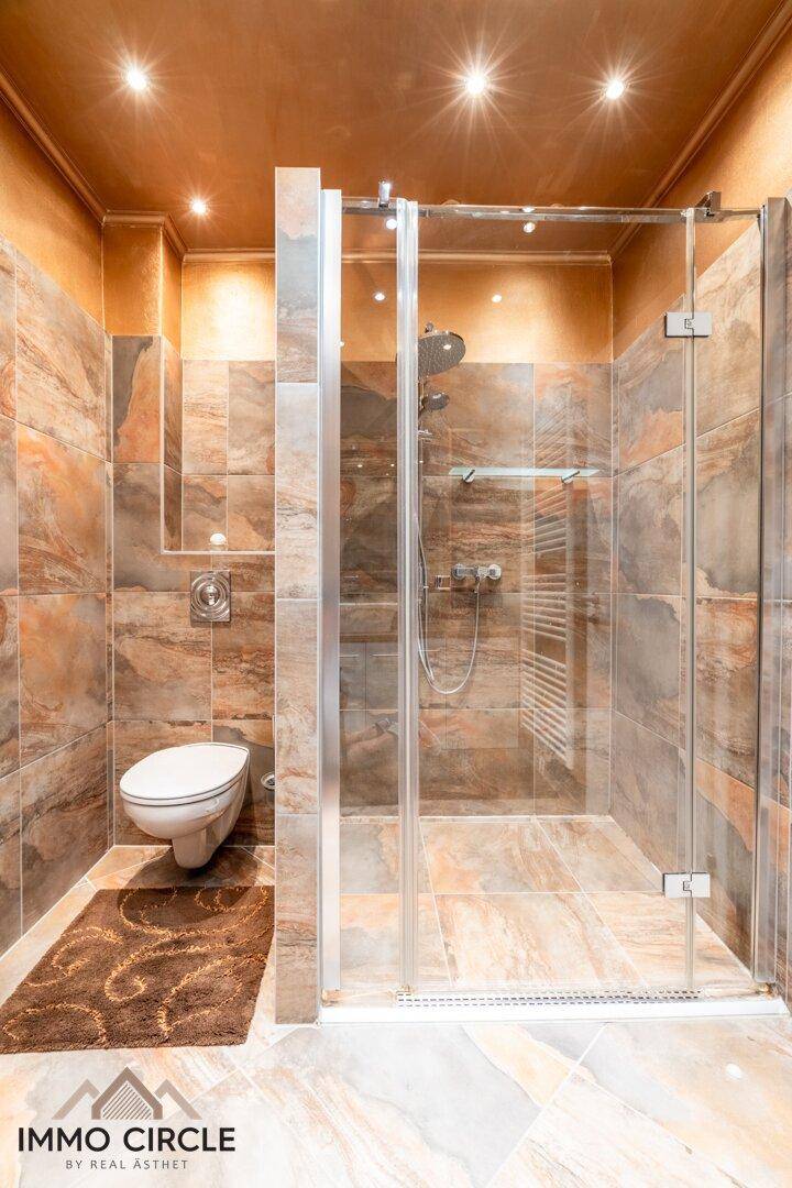 Modernes Badezimmer mit begehbarer Dusche, wandhängendem WC und warmen Fliesen.