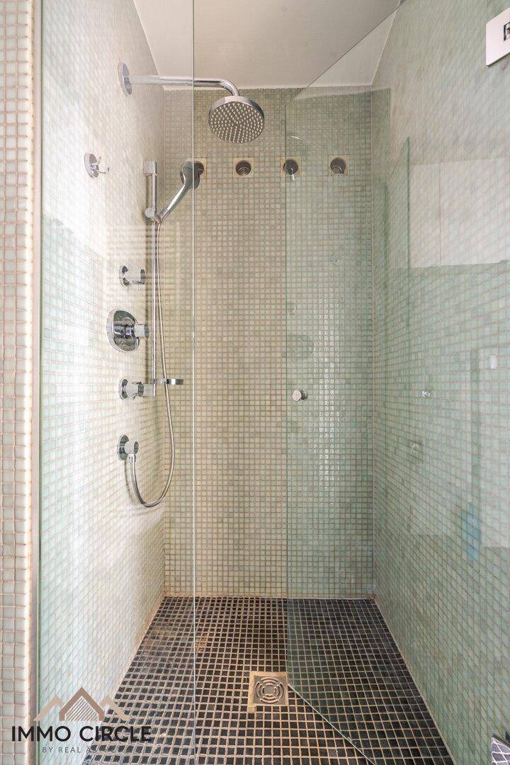 Moderne Duschkabine mit Regendusche und Mosaikfliesen in hellgrünem Farbton.